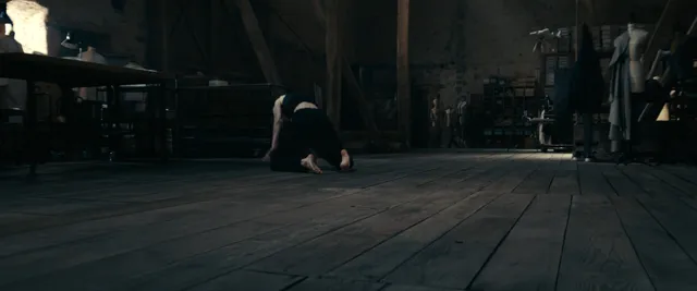 Anne Hathaway posing on a wooden floor in a dark scene.