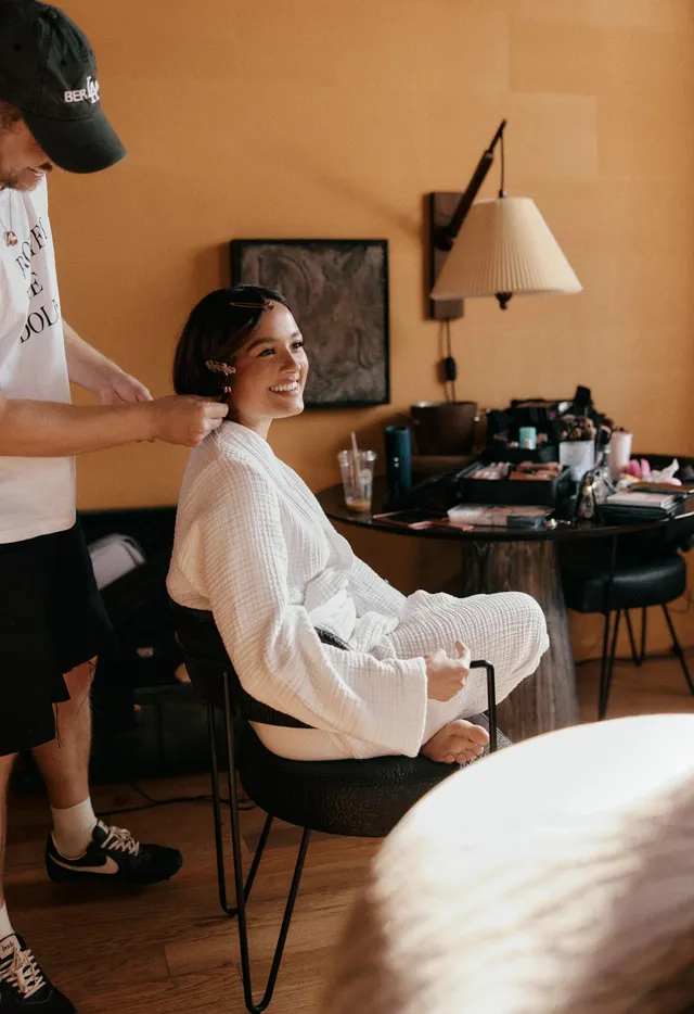 Chase Sui Wonders having makeup applied while sitting barefoot in a white robe.