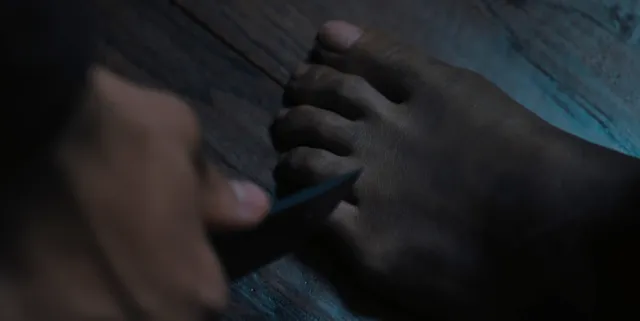 Zoe Saldaña having a foot examined in a dramatic screen scene.