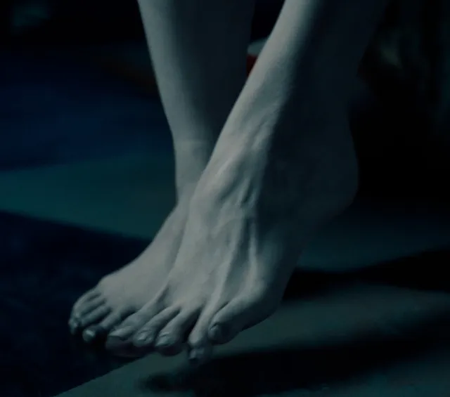 Monica Bellucci a dimly lit screen detail of bare feet.