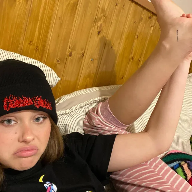 Nicole Wallace taking a selfie while reclining with one bare leg raised.