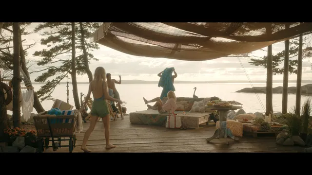 Emily Alyn Lind standing barefoot with friends on an outdoor deck in a scene.