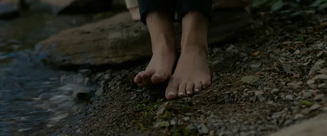 Anna Kendrick showing bare feet on woodland ground.