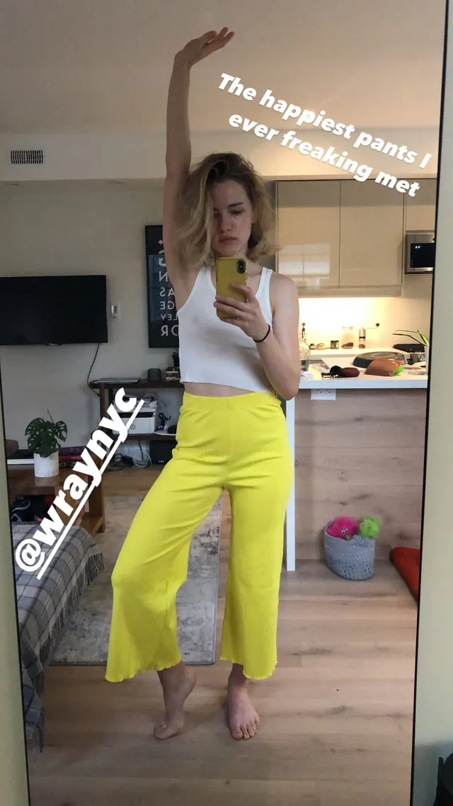 Willa Fitzgerald posing barefoot in yellow trousers for a mirror photograph.