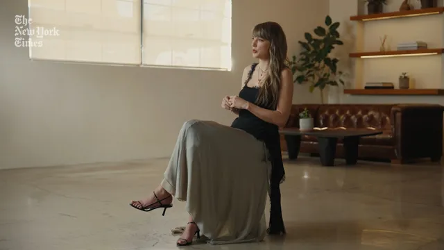 Taylor Swift sitting on a chair in a long skirt.
