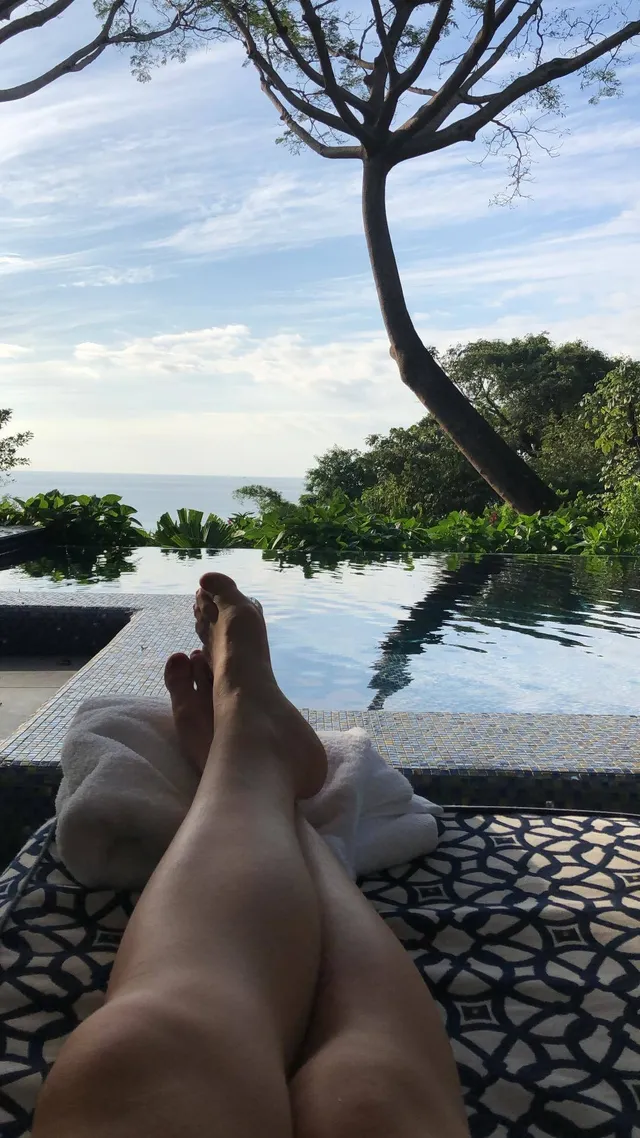 Willa Fitzgerald resting her bare feet beside a pool.