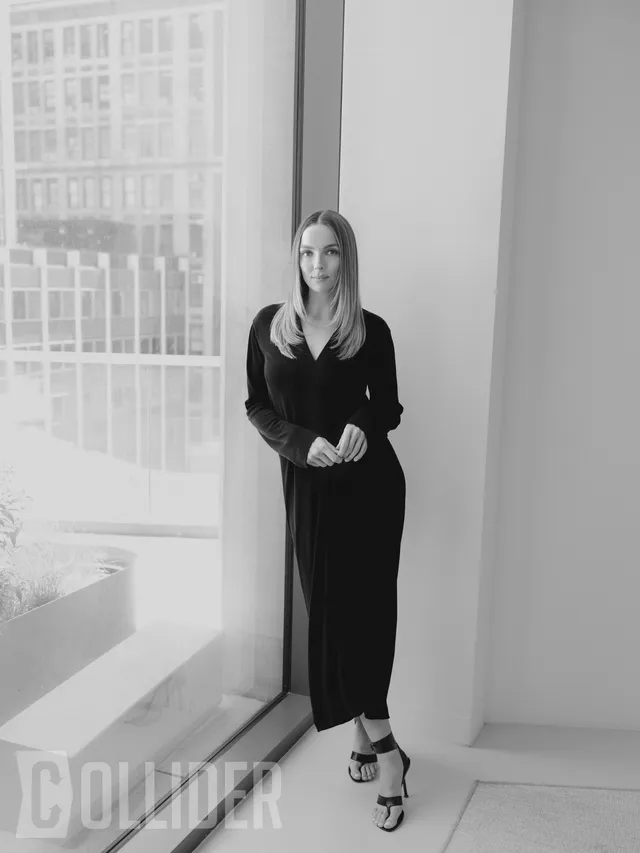 Jodie Comer standing by a window in a monochrome fashion portrait.