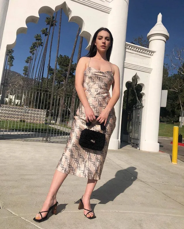 Adelaide Kane posing outside a venue in a patterned dress.