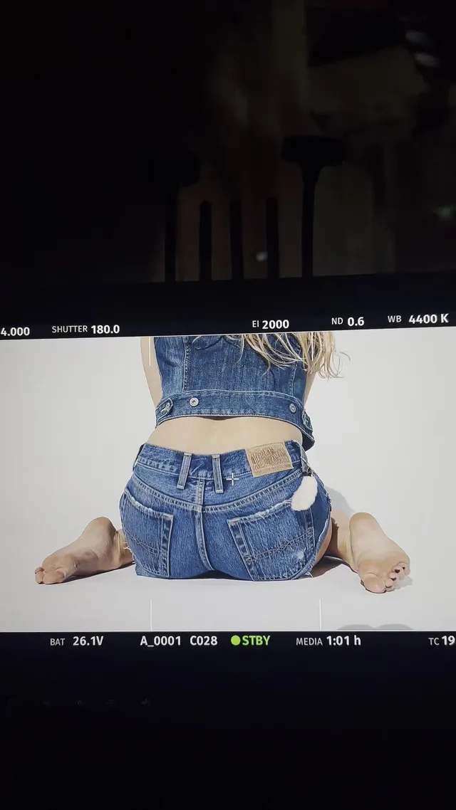 Addison Rae kneeling barefoot in denim during a photo shoot.