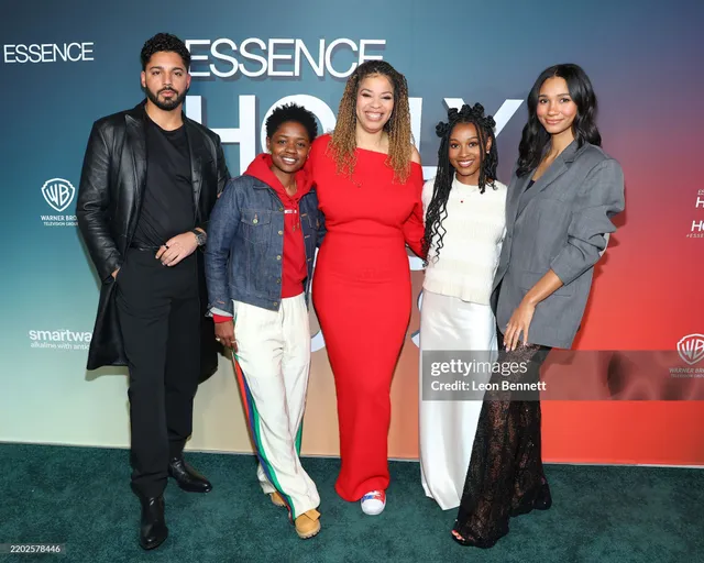 Greta Onieogou posing with fellow performers in a grey blazer and lace trousers.