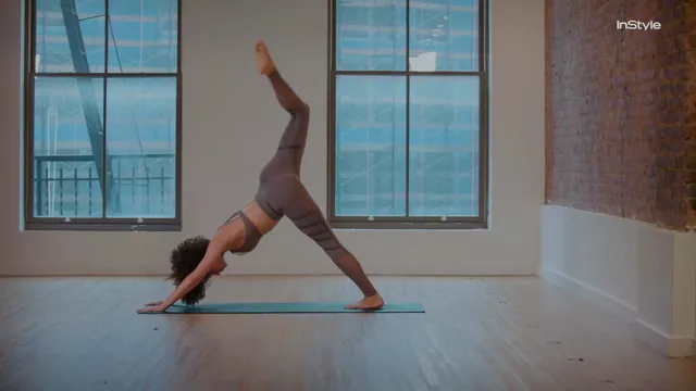 Nathalie Emmanuel balancing in a yoga pose on a studio floor.