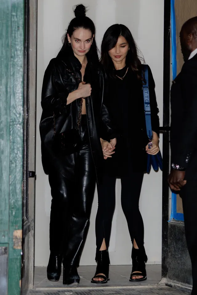 Gemma Chan walking with a companion in a black outfit.