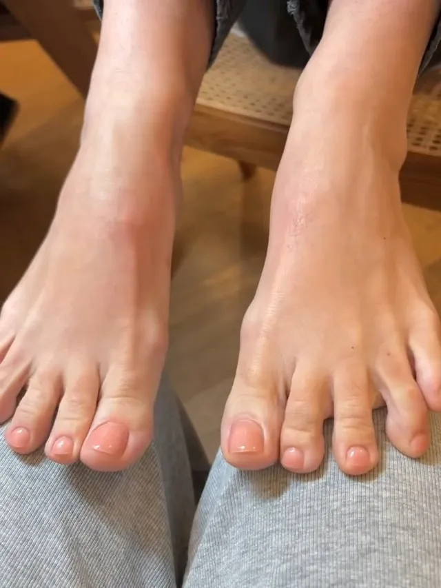 Lily Allen: close view of bare feet resting on grey fabric.