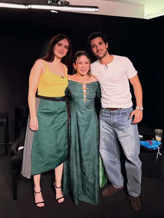 Olivia Cooke posing with two companions in a green skirt.