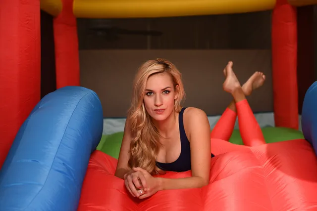 Paige Spiranac lying on an inflatable play structure with her bare feet raised.