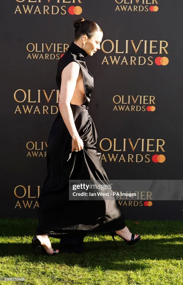 Hayley Atwell walking at an awards event in a black gown.