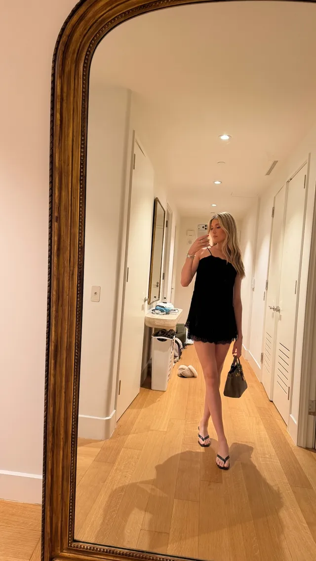 Eugenie Bouchard taking a mirror photograph in flat sandals and a short dark outfit.