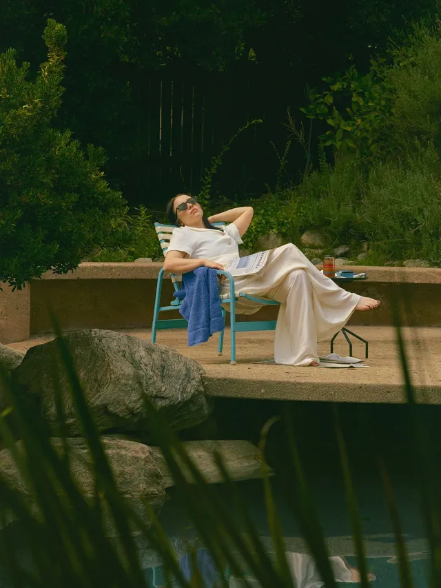 Billie Eilish a pale outfit while seated outdoors.