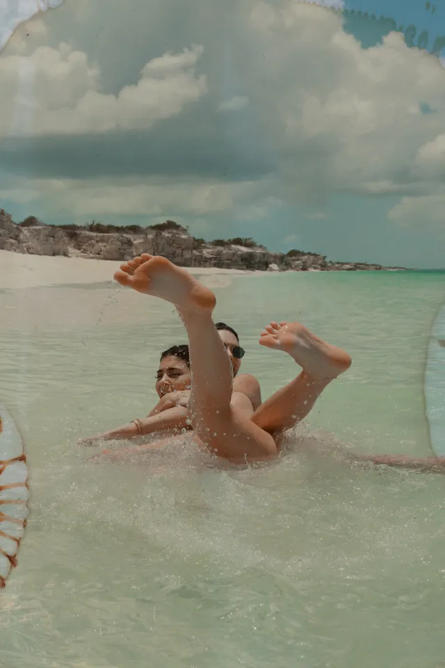 Kendall Jenner floating in shallow seawater with bare feet raised.