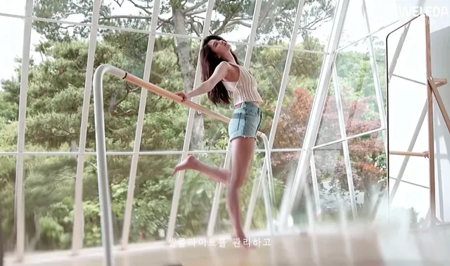Han So-hee posing barefoot by large windows.