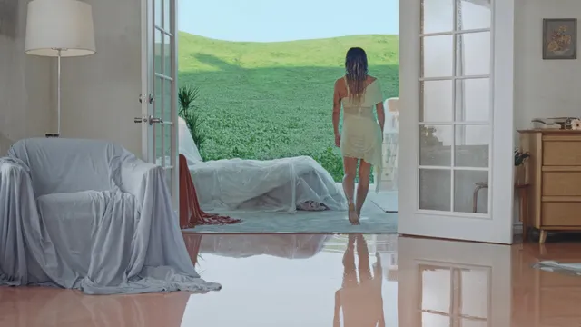Hilary Duff standing barefoot in a bright bedroom.