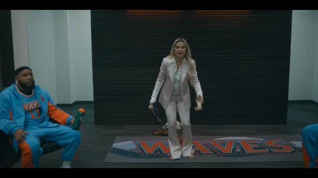 Kate Hudson walking beside a performer in a screen scene.
