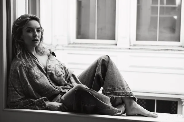Jodie Comer sitting beside a window in a monochrome portrait.