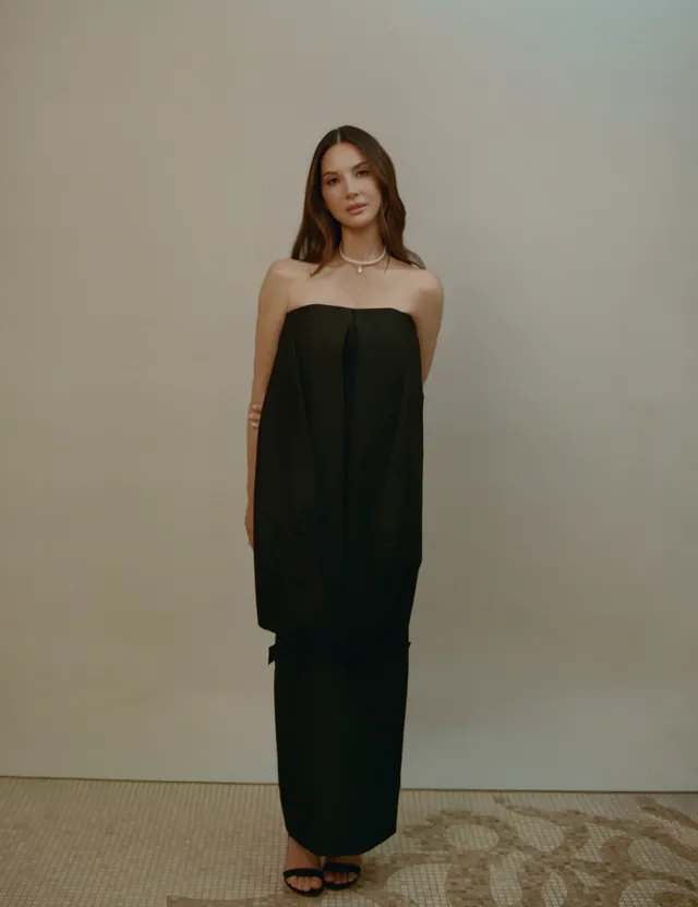 Olivia Munn posing in a long black dress and strappy heels.