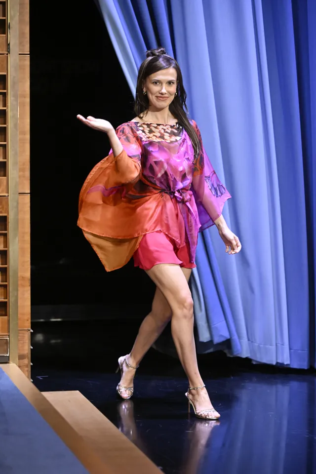 Millie Bobby Brown walking onstage in a pink outfit and metallic heels.