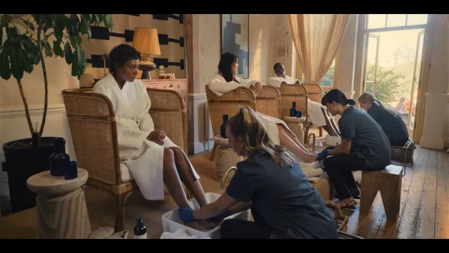 Sophie Wilde sitting barefoot among other people in a film scene.