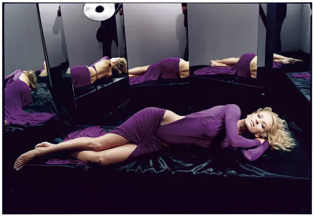 Uma Thurman reclining barefoot in a purple dress.