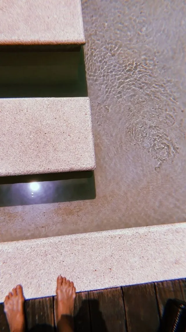 Gigi Hadid a detail of bare feet on a wooden surface.