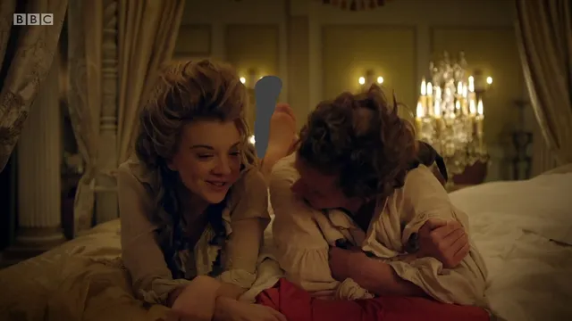 Natalie Dormer sitting with another woman in a bedroom scene.