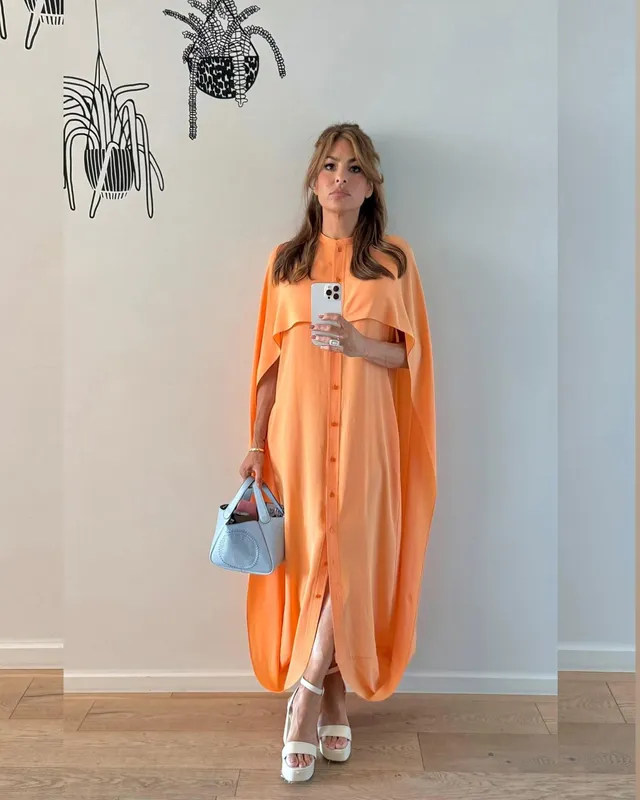 Eva Mendes taking a mirror photograph in an orange dress.