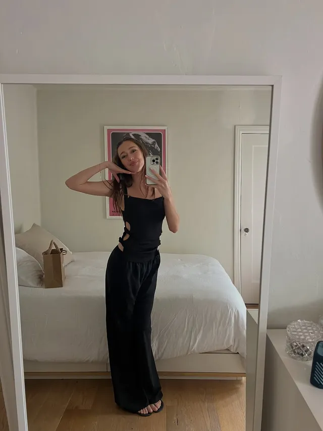 Alycia Debnam-Carey taking a mirror portrait in a black top and trousers.