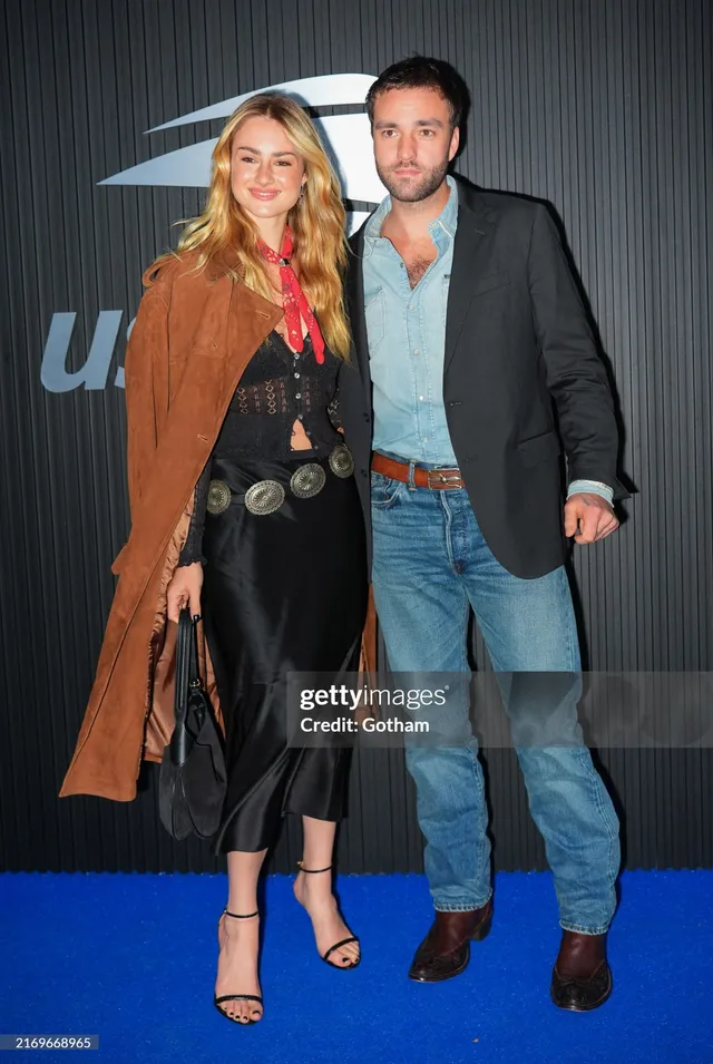 Grace Van Patten posing beside a man in a black outfit and strappy heels.