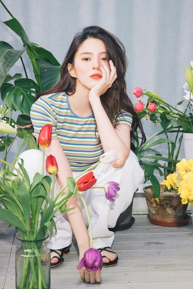 Han So-hee sitting among flowers in black sandals.