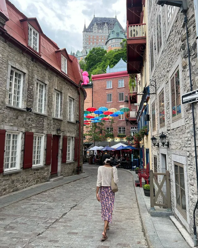 Greta Onieogou walking down a cobbled street in a floral skirt and flats.
