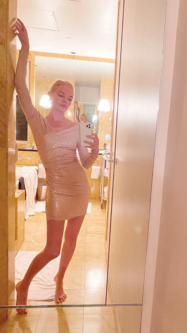 Kate Bosworth taking a mirror photograph in a short pale dress.