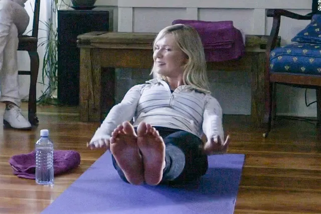 Kirsten Dunst reclining on a purple exercise mat with her soles toward the camera.