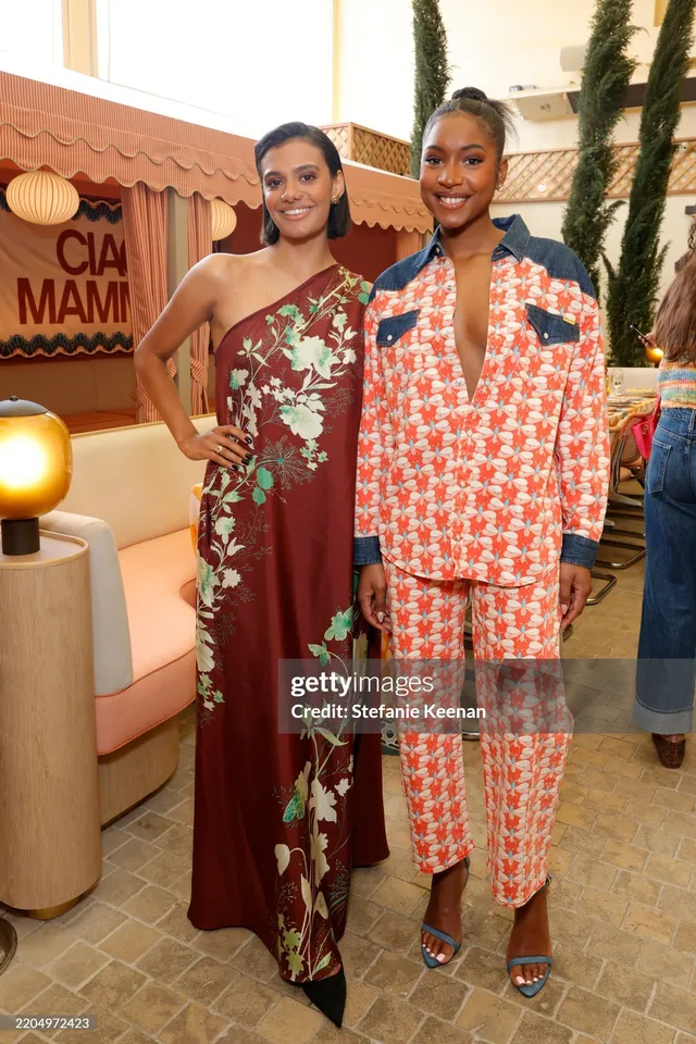 Carlacia Grant posing with a guest in a patterned suit and blue heels.