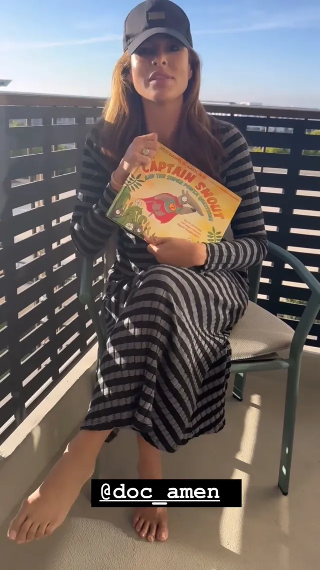 Eva Mendes sitting in a chair wearing striped loungewear.