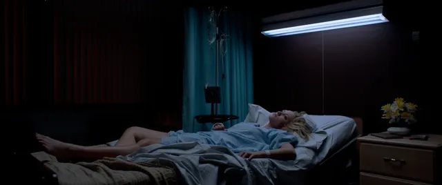 Maika Monroe lying barefoot on a bed in a scene.