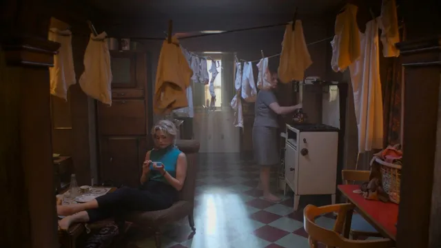 Gemma Arterton sitting in a furnished room in a screen scene.
