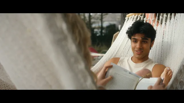 Emily Alyn Lind reclining barefoot in a hammock beside a man.