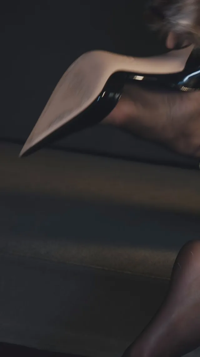 Kendall Jenner showing a black heel in a dimly lit portrait.