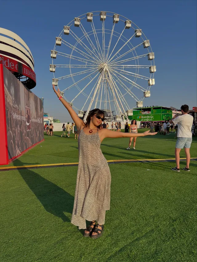 Xochitl Gomez standing outdoors near a Ferris wheel in flat shoes.