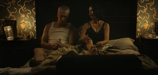 Penélope Cruz a dimly lit screen scene on a bed.