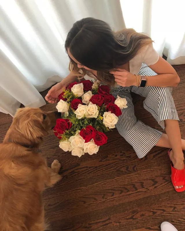 Debby Ryan sitting indoors with flowers beside a dog.