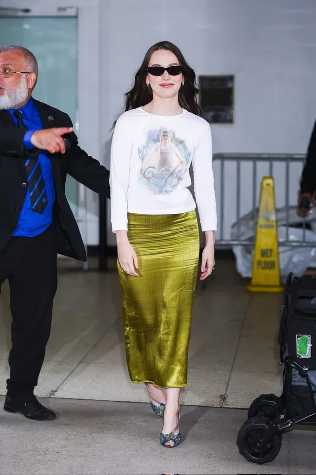 Victoria Pedretti posing outside in a white top and green skirt.